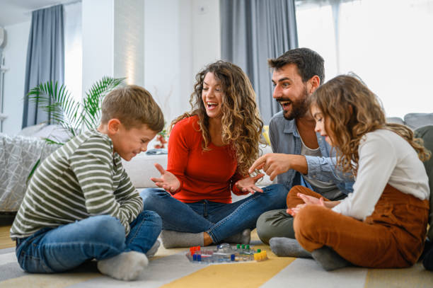 Young parents having fun at home while playing a game with their children.

