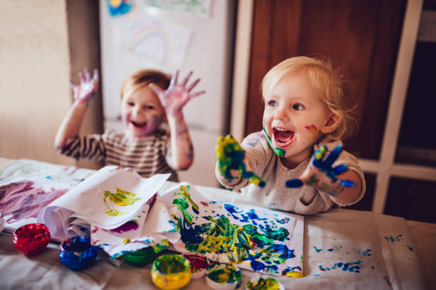 Kids busy with dirty hands and faces having fun being creative with finger painting