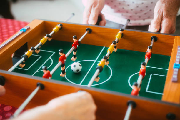 Color image depicting a senior couple playing table football game together. 